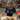 A bodybuilder woman in a sports jersey and wearing a bikini jewelry set with food containers in an indoor setting.
