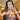 A pair of long, chandelier-style bikini jewelry earrings with silver and multicolored AB rhinestones, displayed by an npc bikini fit model.