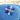 Blue and silver flower-shaped bikini competition earrings on a blue cushion with a wooden surface in the background