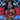 NPC Bikini and Fitness competitor holding medals in front of a competition banner and wearing a pair of diamond bikini competition earrings.