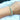 A silver-colored, two-row stretchable bikini jewelry bracelet with multicolored rhinestones displayed on a female's hand.