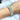 A silver stretchable bikini jewelry bracelet adorned with multicolored AB rhinestones, displayed on a female's hand.