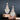 A pair of silver floral crystal chandelier bikini jewelry earrings with AB rhinestones displayed on a wooden stand against a dark background.