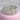 A silver bikini jewelry and competition bracelet adorned with multicolored round rhinestones in an AB pave wave design, displayed on a pink cushion.