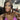 A pair of clear ab pave rhinestone dangle bikini jewelry earrings displayed by an npc bikini fit model.