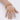 A gold-plated stretch rhinestone bikini jewelry bracelet with clear stones, displayed on a mannequin hand.
