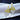 A stretch cocktail bikini jewelry earrings with a flower design accentuated by clear and yellow rhinestones, displayed on a white fabric surface.